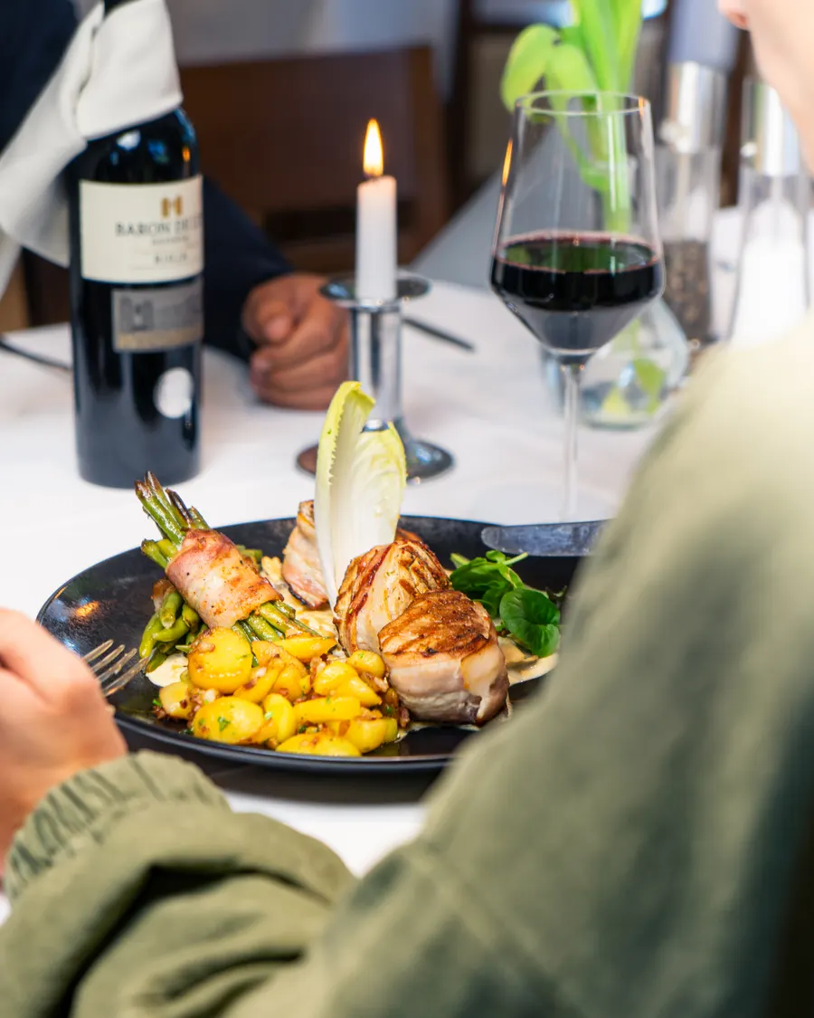 Serviertes Gericht mit Rotwein am festlich gedeckten Tisch im Drögen Hasen